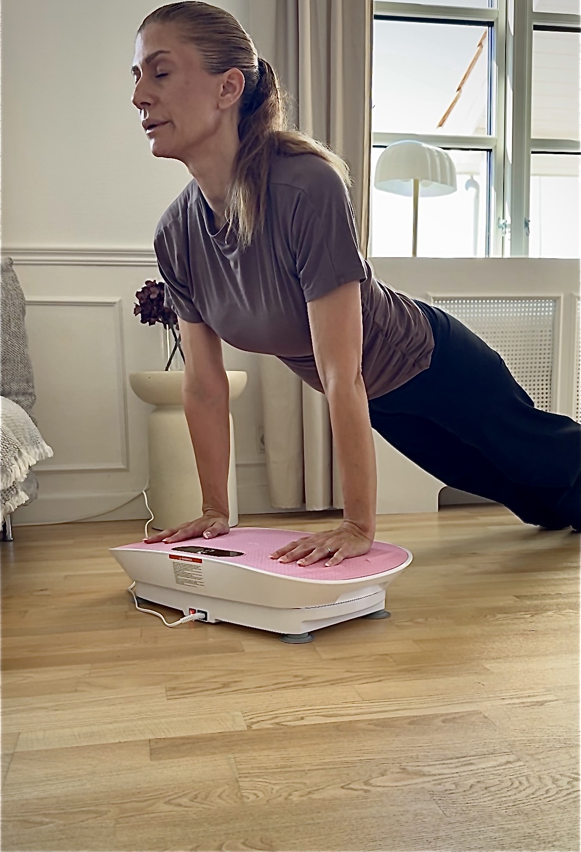Debbie doing a plank on a pink vibration plate at home