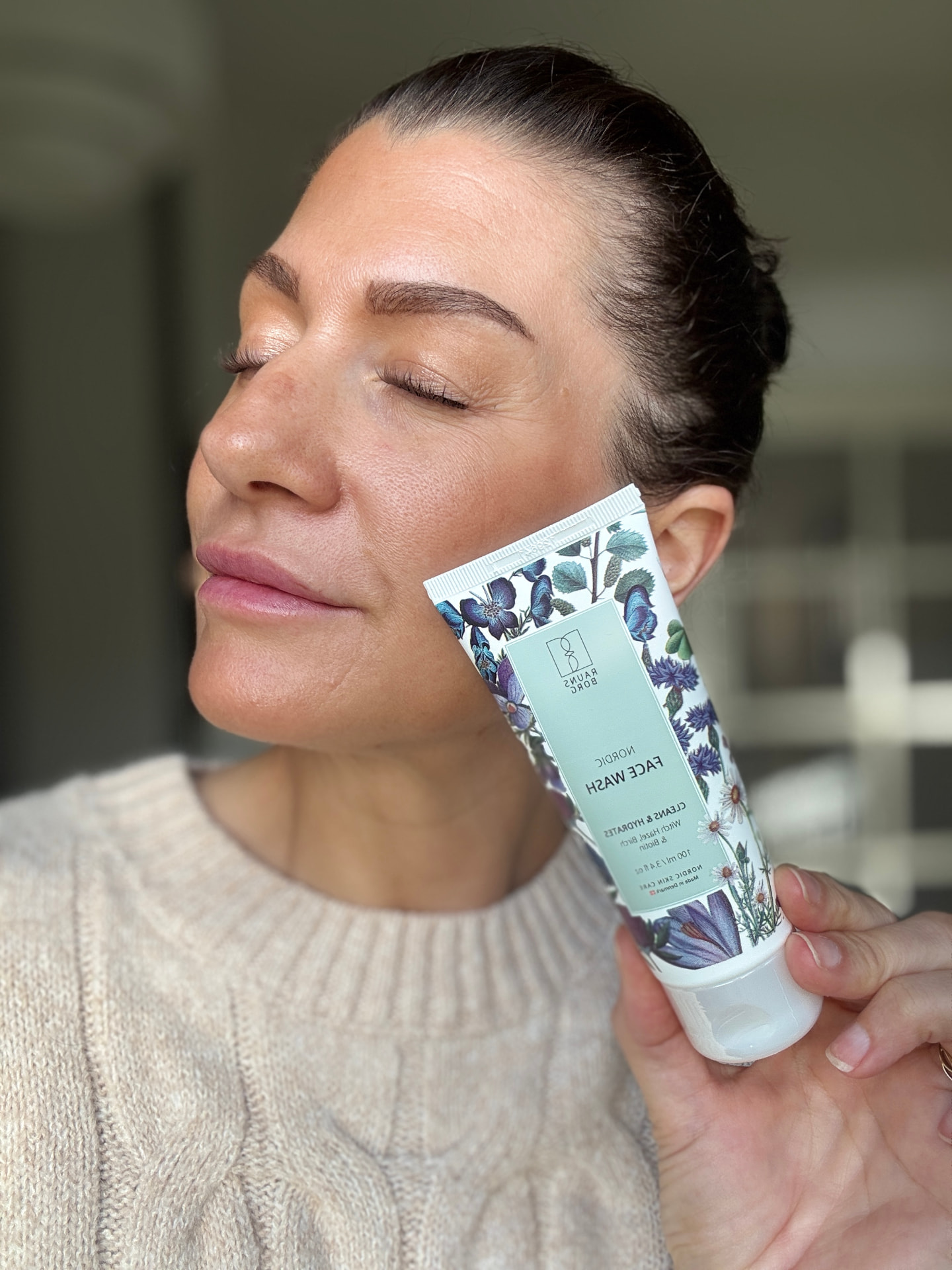 Debbie holding a face wash tube against her cheek