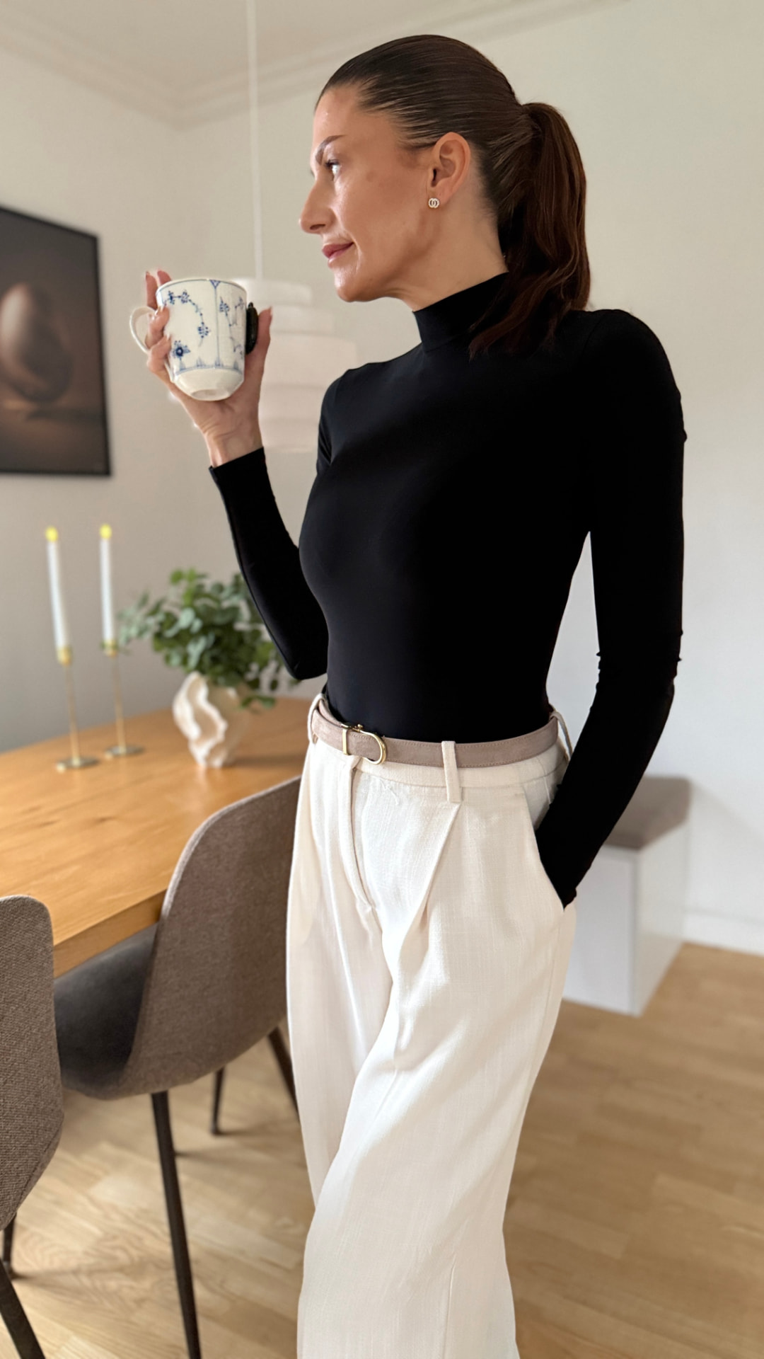 Debbie holding a coffee cup in a bright dining room
