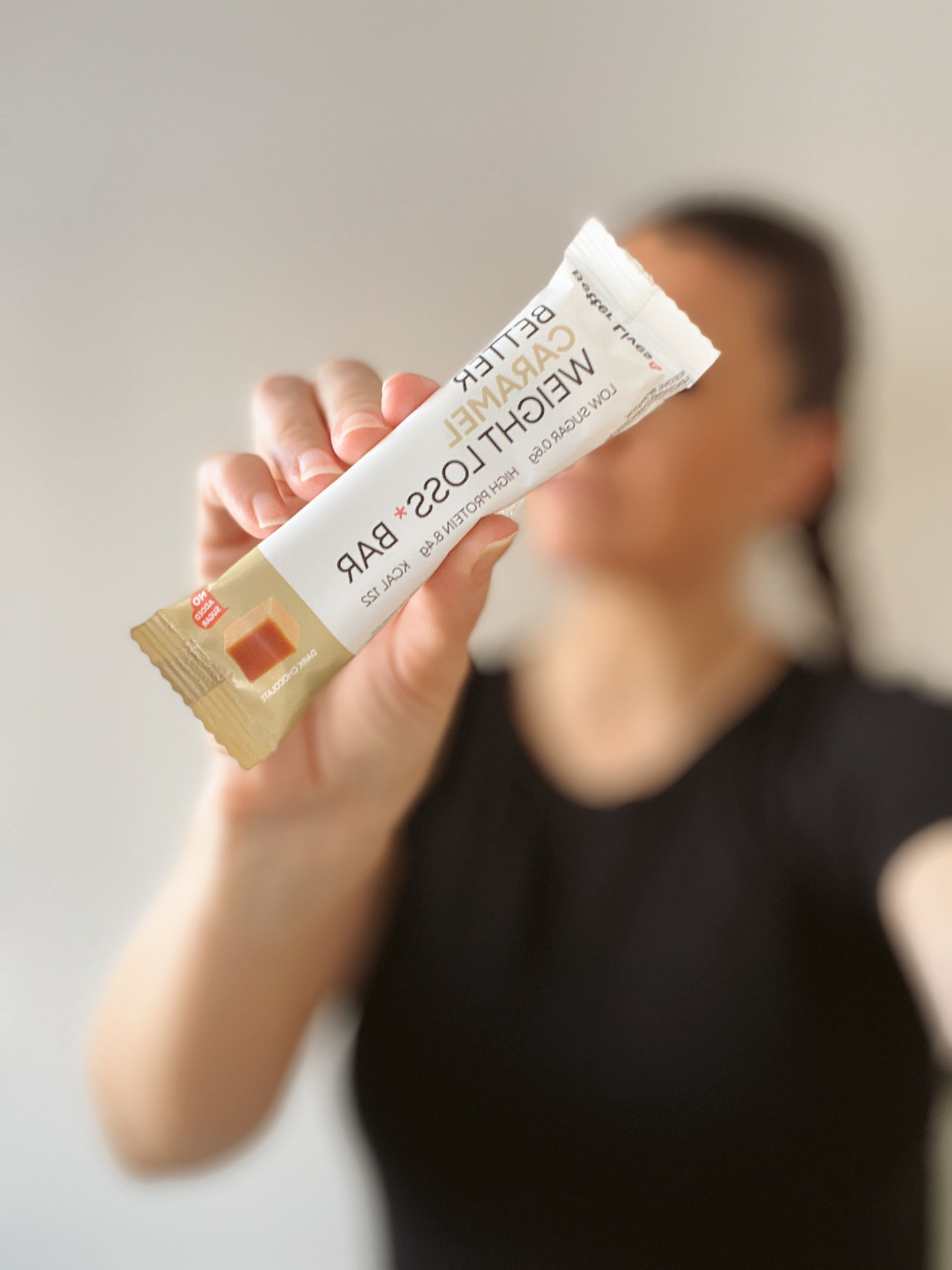 Hand holding a caramel meal bar towards the camera